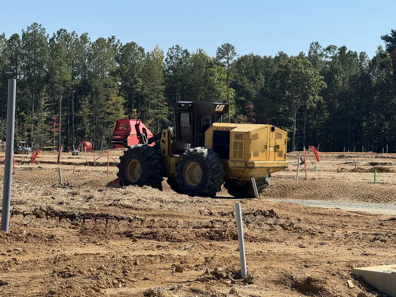 Wheeled feller buncher on a cleared site in the Richmond area with pines behind