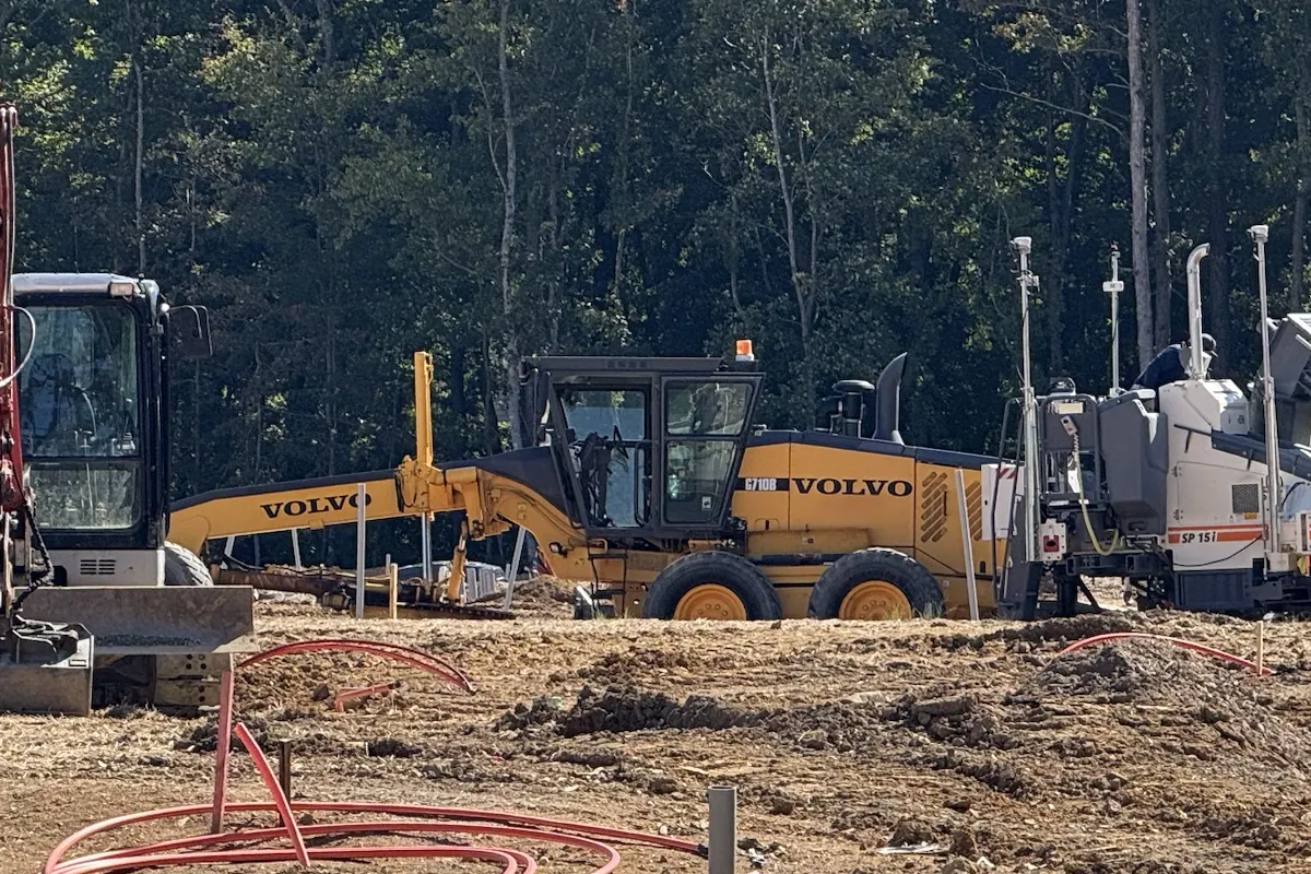 Motor grader on a cleared site, with an excavator beside it
